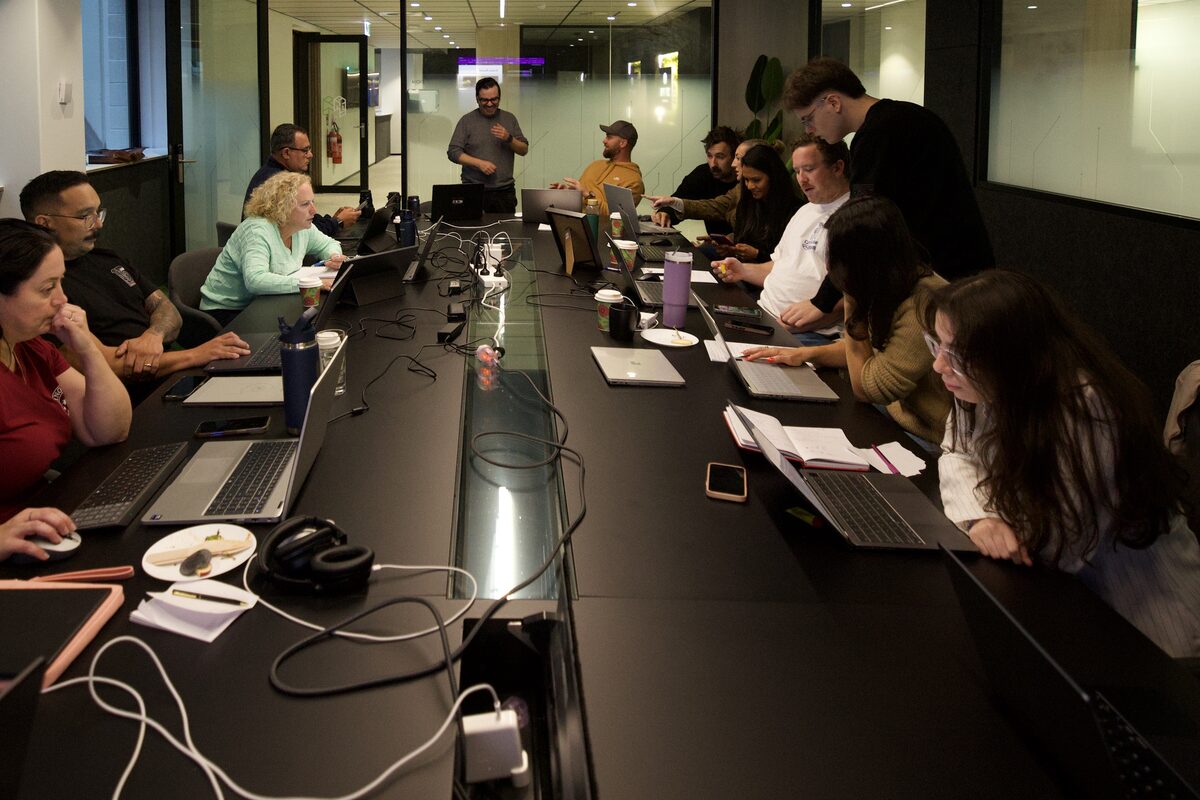 People working on laptops at a long table during one of our hands-on AI sessions in Perth