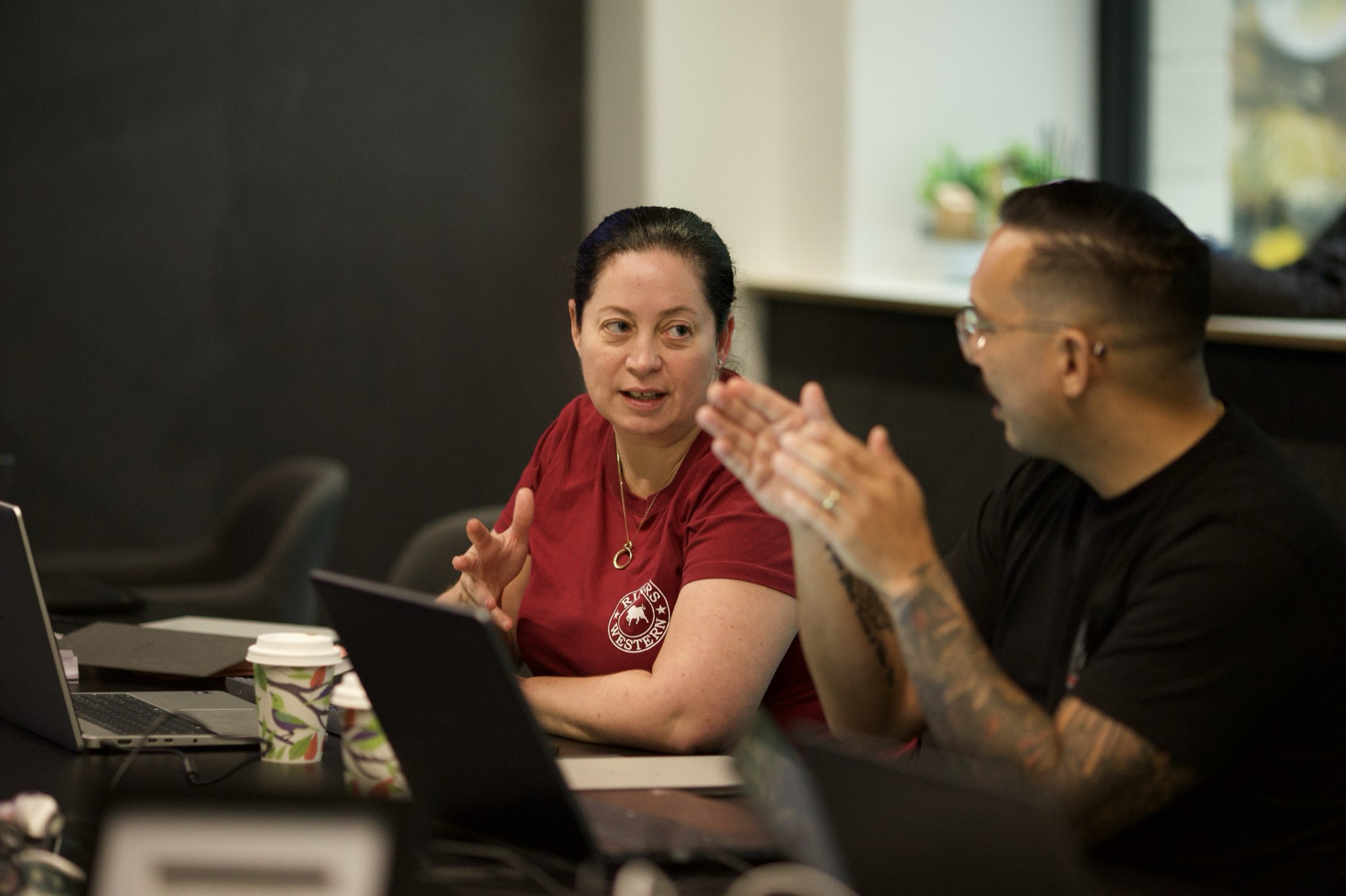 Two staff members talking through their admin workload at a workshop table