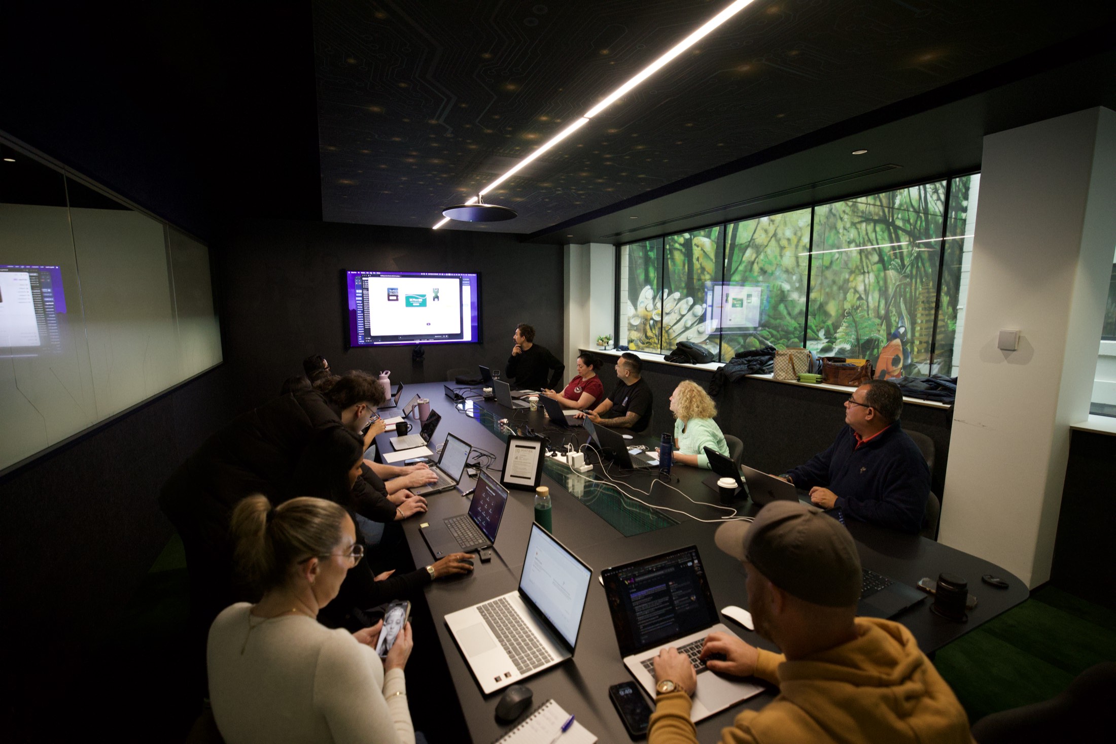 A Scalify Microsoft AI training session in a Perth boardroom, with slides on the wall screen and the whole team working on laptops